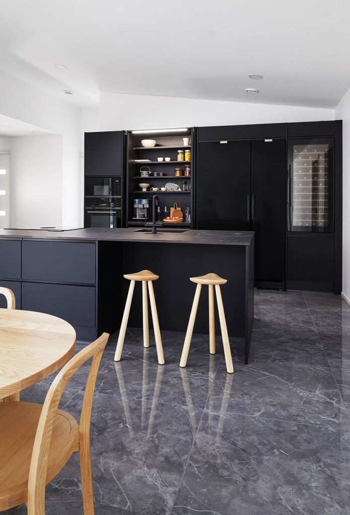 Mustat kiintokalusteet ja tummat lattialaatat tuovat eleganttia ryhtiä keittiöön, jossa musta on nostettu aksenttivärin sijasta päärooliin.